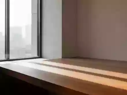 Ein minimalistischer, heller Raum mit klaren architektonischen Linien und sanftem Lichteinfall auf einer Holzoberfläche. - Foto: über boerse-global.de