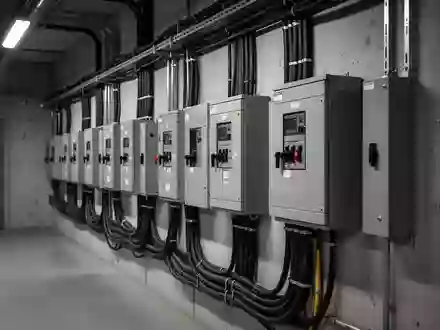 Ein technischer Raum mit grauen Stromverteilerschränken und Leitungen an einer Betonwand. - Foto: über boerse-global.de