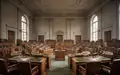 Leerer Plenarsaal eines Landtags mit hölzernen Sitzreihen und historischer Architektur bei natürlichem Lichteinfall. - Foto: über boerse-global.de