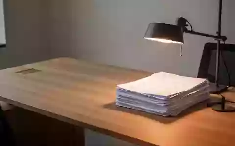 Ein minimalistischer Arbeitsplatz mit einem Stapel geordneter Dokumente auf einem Holztisch unter warmem Licht. - Foto: über boerse-global.de