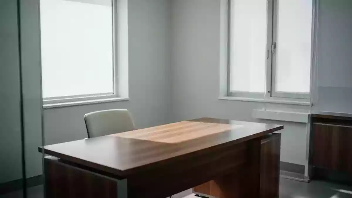 Ein minimalistischer, heller Behandlungsraum in einer medizinischen Einrichtung mit leerem Stuhl und Schreibtisch. Illustration mit AI erstellt.