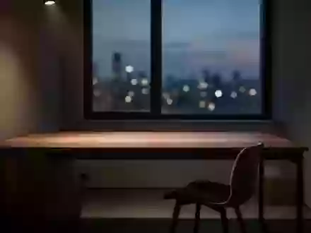 Ein minimalistisch eingerichteter, leerer Schreibtisch in einem dunklen Raum bei Dämmerung mit abstraktem Stadtlicht im Hintergrund. - Foto: über boerse-global.de
