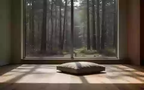 Ein minimalistisch gestalteter, lichtdurchfluteter Raum mit einem Bodenkissen und Blick auf einen ruhigen Wald. - Foto: über boerse-global.de