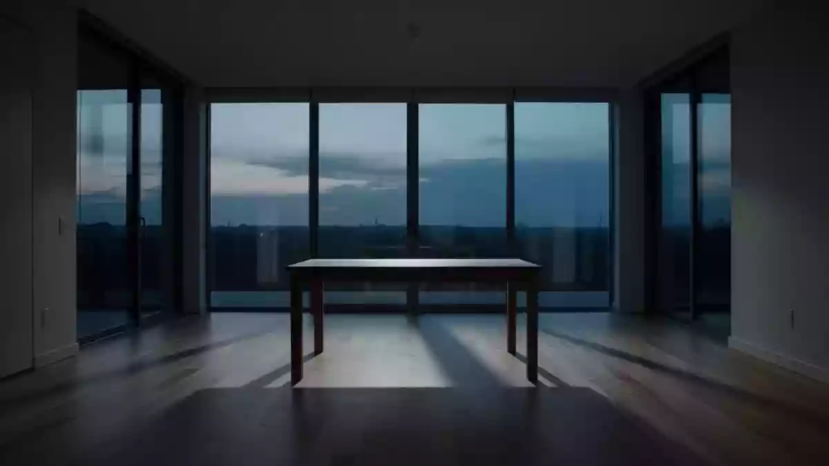 Ein minimalistisches, leeres Wohnzimmer in der Abenddämmerung, das eine Atmosphäre von Stille und emotionaler Distanz vermittelt. Illustration mit AI erstellt.