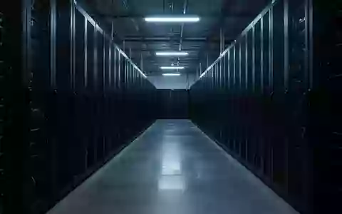 Ein langer, menschenleerer Gang in einem Rechenzentrum mit hoch aufragenden, dunklen Server-Racks in kühler Beleuchtung. - Foto: über boerse-global.de