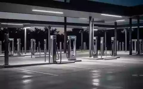 Eine moderne, menschenleere Ladestation für Elektrofahrzeuge bei Dämmerung mit minimalistischen Ladesäulen auf einem Betonplatz. - Foto: über boerse-global.de