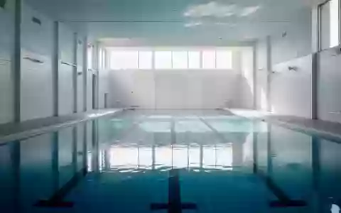 Ein leeres, modernes Hallenbad mit klarem blauem Wasser und hellen Fliesen in einer ruhigen Atmosphäre. - Foto: über boerse-global.de