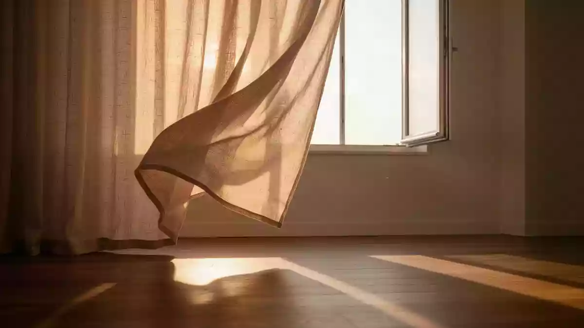 Ein ruhiger, minimalistischer Raum mit weichen, im Wind wehenden Leinenvorhängen und sanftem Sonnenlicht auf einem Holzboden. Illustration mit AI erstellt.