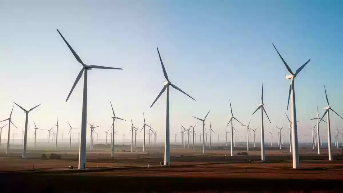 Weitläufige Windkraftanlage in einer offenen Landschaft unter klarem Himmel als Symbol für nachhaltige Klimaziele. Illustration mit AI erstellt.
