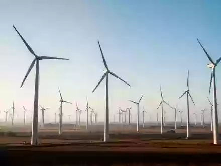 Weitläufige Windkraftanlage in einer offenen Landschaft unter klarem Himmel als Symbol für nachhaltige Klimaziele. - Foto: über boerse-global.de