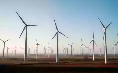 Weitläufige Windkraftanlage in einer offenen Landschaft unter klarem Himmel als Symbol für nachhaltige Klimaziele. - Foto: über boerse-global.de