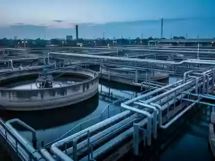 Industrielle Wasseraufbereitungsanlage mit großen Betonbecken und Rohrleitungen bei Dämmerung. - Foto: über boerse-global.de