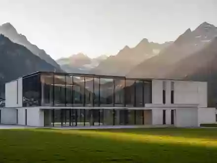 Ein modernes, minimalistisches Verwaltungsgebäude in einer Schweizer Alpenlandschaft bei Sonnenuntergang. - Foto: über boerse-global.de