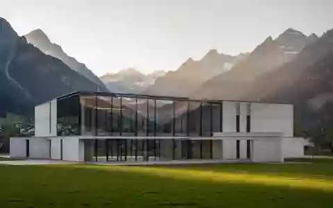 Ein modernes, minimalistisches Verwaltungsgebäude in einer Schweizer Alpenlandschaft bei Sonnenuntergang. - Foto: über boerse-global.de