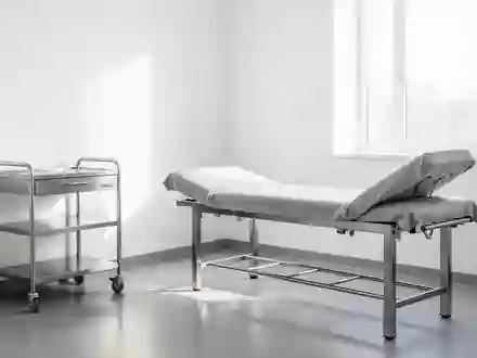 Ein heller, minimalistischer Behandlungsraum in einer Klinik mit einer Untersuchungsliege und einem medizinischen Wagen. - Foto: über boerse-global.de