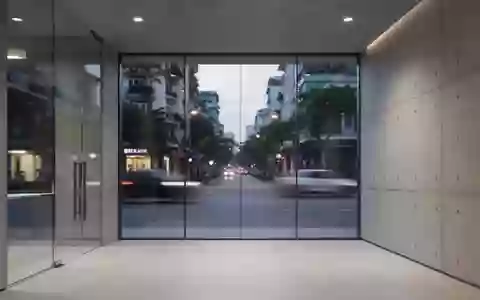 Ein minimalistisch gestalteter Innenraum einer modernen Bank mit Betonwänden und großen Glasfronten bei Dämmerung. - Foto: über boerse-global.de