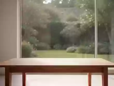 Ein minimalistischer, lichtdurchfluteter Raum mit einem leeren Holztisch und Blick auf einen ruhigen Garten. - Foto: über boerse-global.de