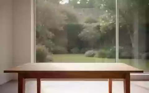 Ein minimalistischer, lichtdurchfluteter Raum mit einem leeren Holztisch und Blick auf einen ruhigen Garten. - Foto: über boerse-global.de