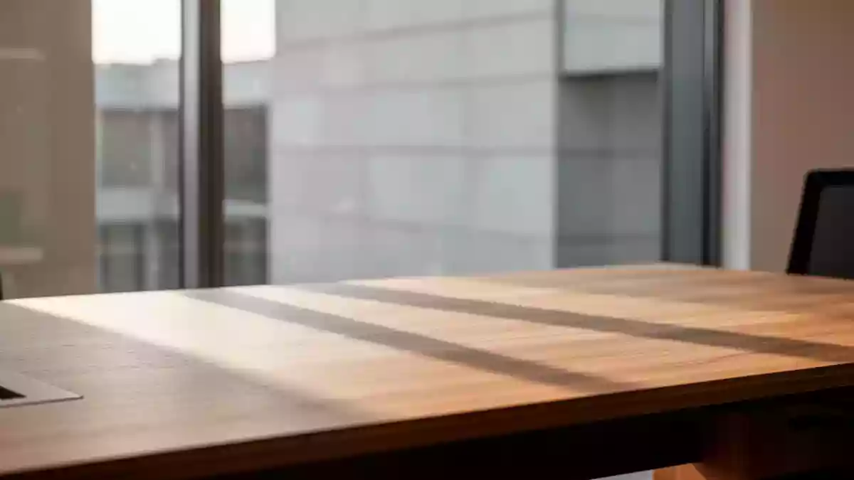 Ein minimalistischer, aufgeräumter Arbeitsplatz mit einer hölzernen Schreibtischoberfläche und natürlichem Lichteinfall. Illustration mit AI erstellt.