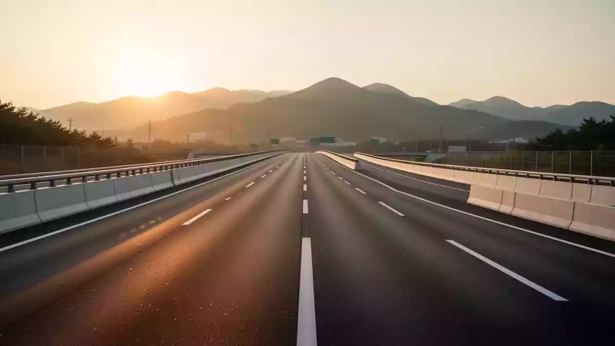 Eine leere, modern gestaltete Autobahn mit klarer Fahrbahnmarkierung in einer hügeligen Landschaft bei Sonnenuntergang. Illustration mit AI erstellt.