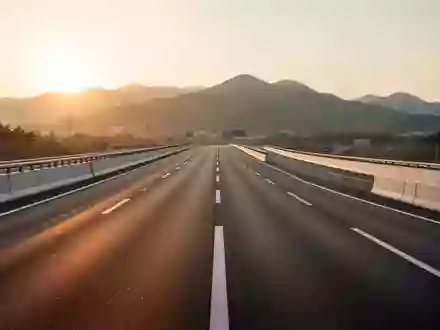Eine leere, modern gestaltete Autobahn mit klarer Fahrbahnmarkierung in einer hügeligen Landschaft bei Sonnenuntergang. - Foto: über boerse-global.de