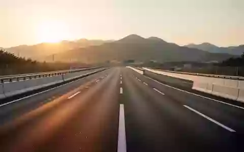 Eine leere, modern gestaltete Autobahn mit klarer Fahrbahnmarkierung in einer hügeligen Landschaft bei Sonnenuntergang. - Foto: über boerse-global.de