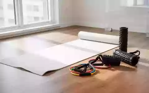 Ein minimalistischer Physiotherapieraum mit einer Yogamatte, Widerstandsbändern und einer Faszienrolle auf einem Holzboden. - Foto: über boerse-global.de