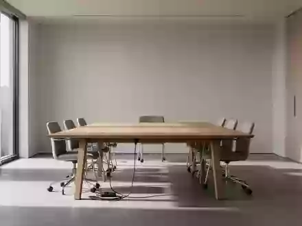 Ein minimalistisch eingerichteter Konferenzraum mit einem leeren Holztisch in einem hellen, sonnendurchfluteten Büro. - Foto: über boerse-global.de