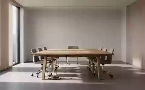 Ein minimalistisch eingerichteter Konferenzraum mit einem leeren Holztisch in einem hellen, sonnendurchfluteten Büro. - Foto: über boerse-global.de