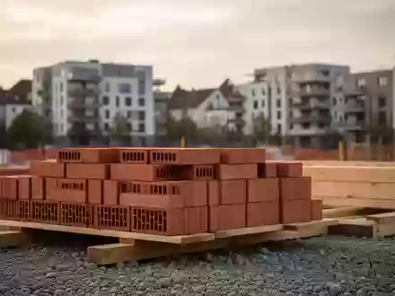 Baustelle mit ordentlich gestapelten Ziegeln und Holzbalken vor einer Kulisse moderner Wohngebäude in einer Stadt. - Foto: über boerse-global.de