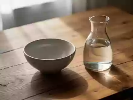 Ein minimalistischer Holztisch mit einer Keramikschale und einer Wasserkaraffe bei sanftem Tageslicht. - Foto: über boerse-global.de