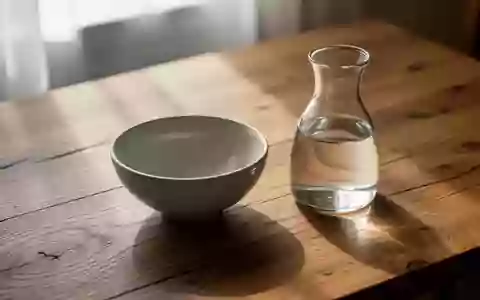 Ein minimalistischer Holztisch mit einer Keramikschale und einer Wasserkaraffe bei sanftem Tageslicht. - Foto: über boerse-global.de