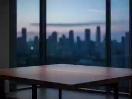 Ein minimalistischer, modern eingerichteter Raum bei Dämmerung mit Blick auf eine unscharfe Skyline. - Foto: über boerse-global.de