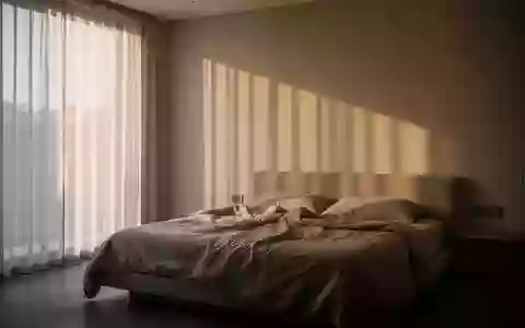 Ein minimalistisch eingerichtetes Schlafzimmer am frühen Morgen mit sanftem, durch Vorhänge einfallendem Tageslicht. - Foto: über boerse-global.de