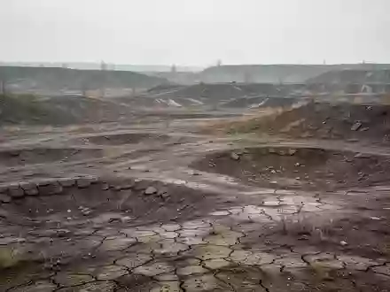 Eine weitläufige, unebene Landschaft in einer ehemaligen Bergbauregion mit aufgebrochenem Boden und karger Vegetation. - Foto: über boerse-global.de