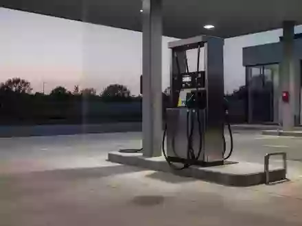 Eine leere Tankstelle bei Dämmerung mit Fokus auf den Boden und die Basis einer Zapfsäule. - Foto: über boerse-global.de