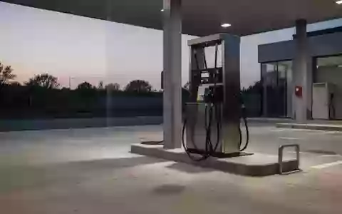 Eine leere Tankstelle bei Dämmerung mit Fokus auf den Boden und die Basis einer Zapfsäule. - Foto: über boerse-global.de
