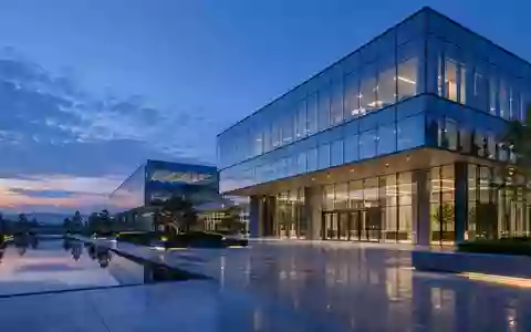 Ein modernes, minimalistisches Bürogebäude in der Abenddämmerung mit klaren architektonischen Linien und Glasfassade. - Foto: über boerse-global.de