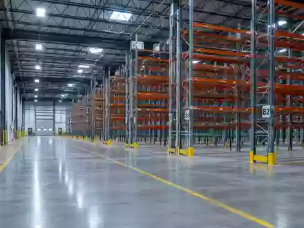 Ein weites, leeres Industrie-Logistikzentrum mit hohen Regalsystemen und poliertem Betonboden. - Foto: über boerse-global.de