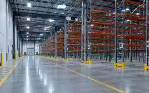 Ein weites, leeres Industrie-Logistikzentrum mit hohen Regalsystemen und poliertem Betonboden. - Foto: über boerse-global.de