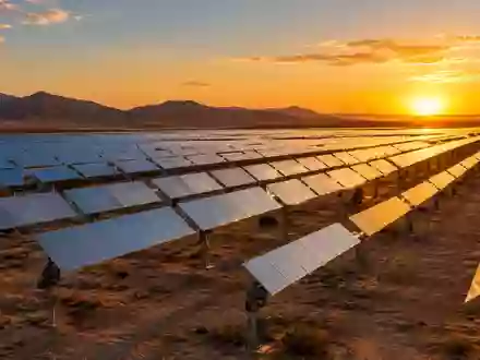 Weitläufiger Solarpark mit nachgeführten Solarmodulen in einer Wüstenlandschaft bei Sonnenuntergang. - Foto: über boerse-global.de