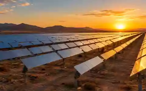 Weitläufiger Solarpark mit nachgeführten Solarmodulen in einer Wüstenlandschaft bei Sonnenuntergang. - Foto: über boerse-global.de