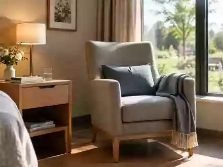 Ein sonnendurchflutetes, ruhiges Zimmer in einem Pflegeheim mit einem Holztisch und einem Sessel am Fenster. - Foto: über boerse-global.de
