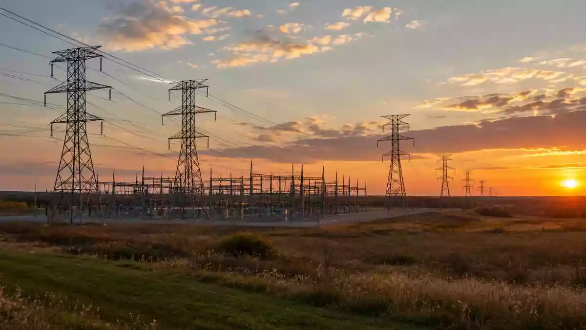 Eine weitläufige Landschaft mit Hochspannungsmasten und Stromleitungen bei Sonnenuntergang in Ohio. Illustration mit AI erstellt.