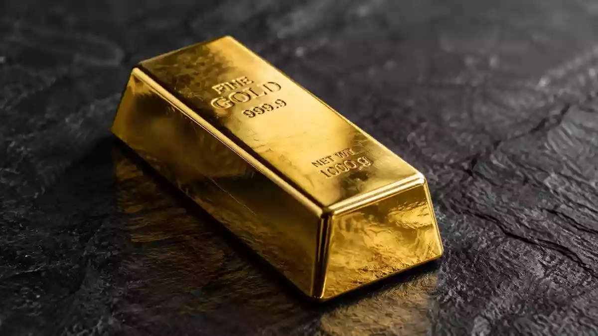 Ein glänzender Goldbarren auf einer dunklen Schieferplatte mit weicher, cinematischer Beleuchtung. Illustration mit AI erstellt.