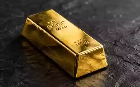 Ein glänzender Goldbarren auf einer dunklen Schieferplatte mit weicher, cinematischer Beleuchtung. - Foto: über boerse-global.de