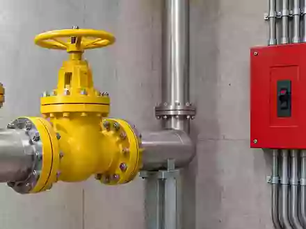 Industrielle Umgebung mit einem gelben Ventil und einem roten Schalter an einer Betonwand. - Foto: über boerse-global.de