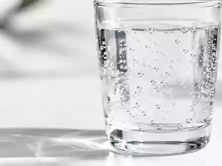 Ein klares Glas mit sprudelndem Wasser auf einem minimalistischen weißen Untergrund. - Foto: über boerse-global.de
