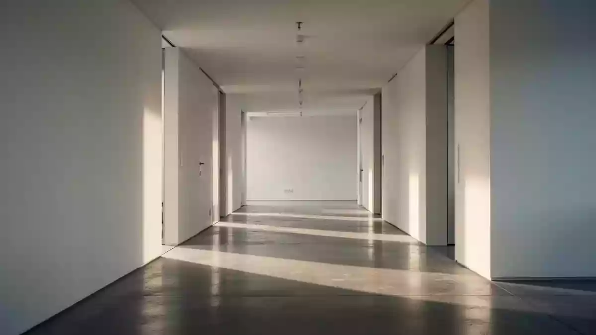 Ein leerer, minimalistischer Büroflur mit weichem Licht und klaren Schatten auf einem Betonboden. Illustration mit AI erstellt.