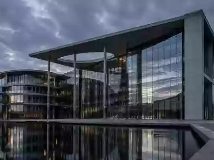 Moderne Glas- und Stahlfassade eines Behördengebäudes bei Dämmerung, Architekturaufnahme ohne Text. - Foto: über boerse-global.de
